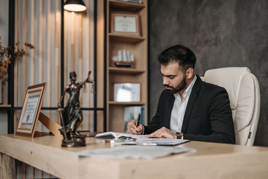 A focused lawyer in an office setting writing and reviewing legal documents, symbolizing expertise and professionalism.